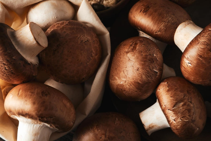 Fresh chestnut mushrooms displayed in a basket with a rustic background