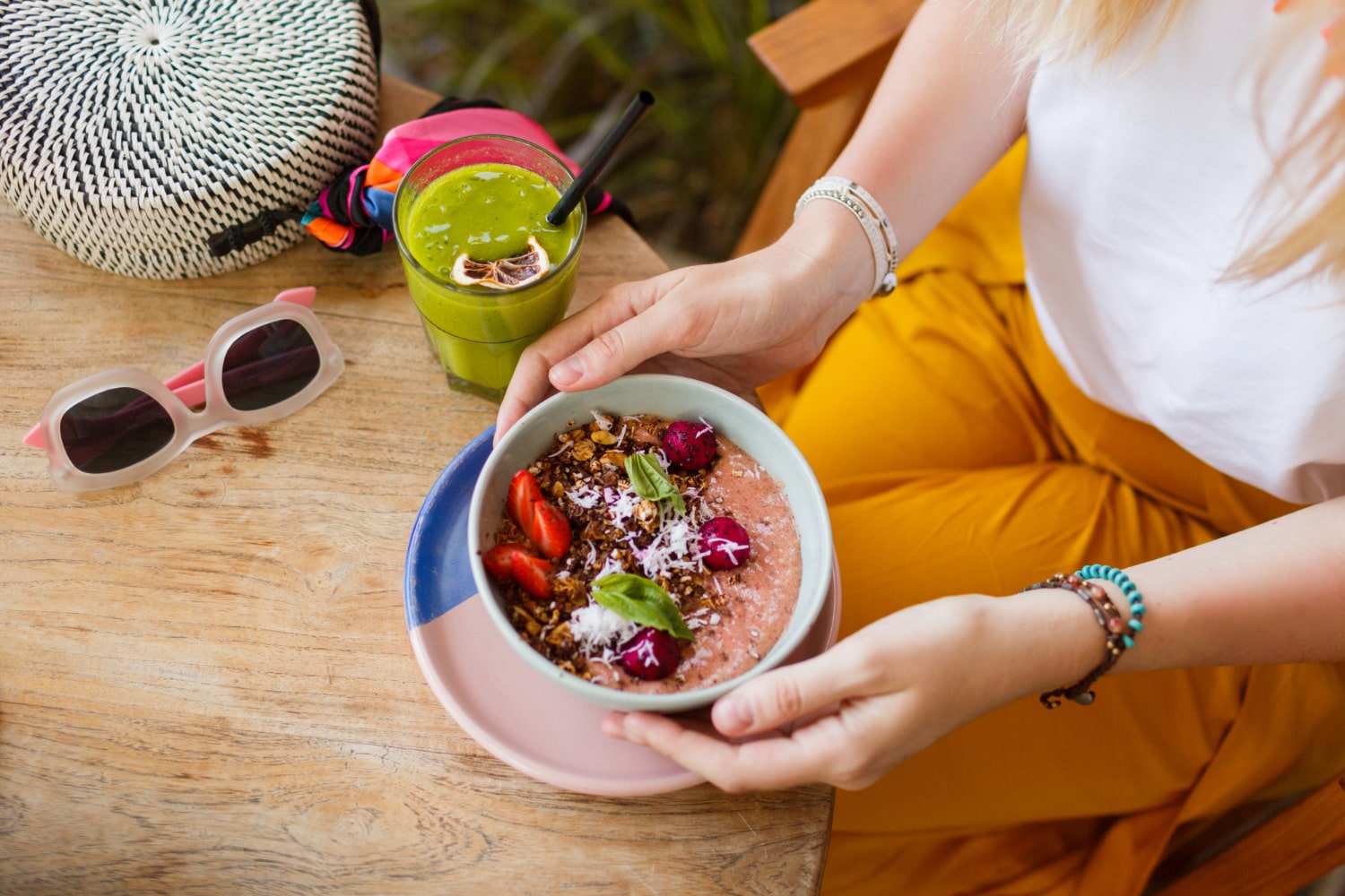 Close-up of a colorful smoothie bowl with fresh fruit and a green juice